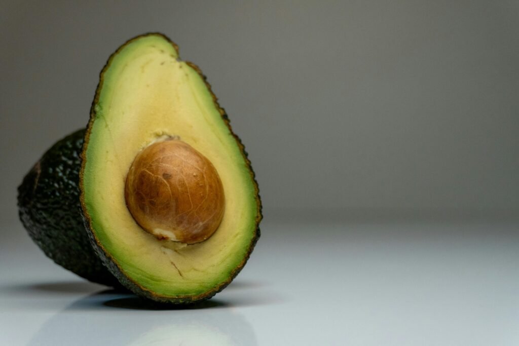 pexels-photo-19808830-19808830 Half avocado on gray background, showcasing fresh green and brown hues for food photography.
